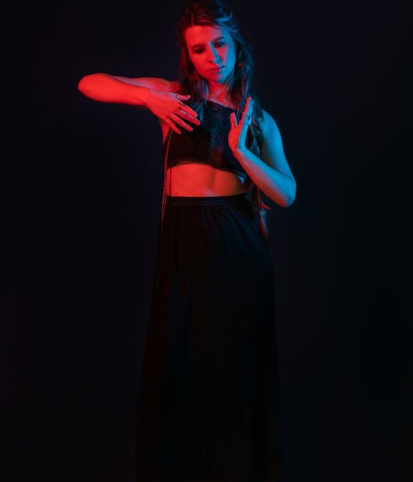 Woman performing a graceful yoga pose in a dark, atmospheric studio.